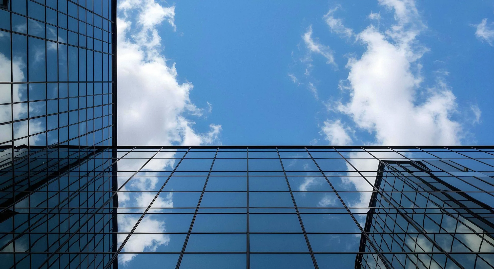 A glass-clad high-rise reflecting blue sky and clouds, the kind of structure an IEC 62305 risk assessment evaluates