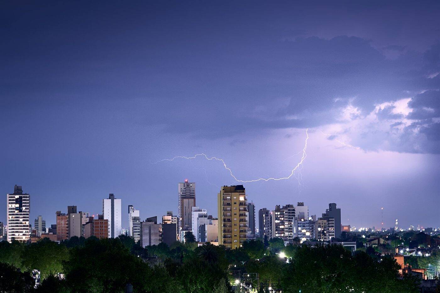 A lightning strike over a city skyline at dusk, the kind of exposure an IEC 62305 risk assessment quantifies
