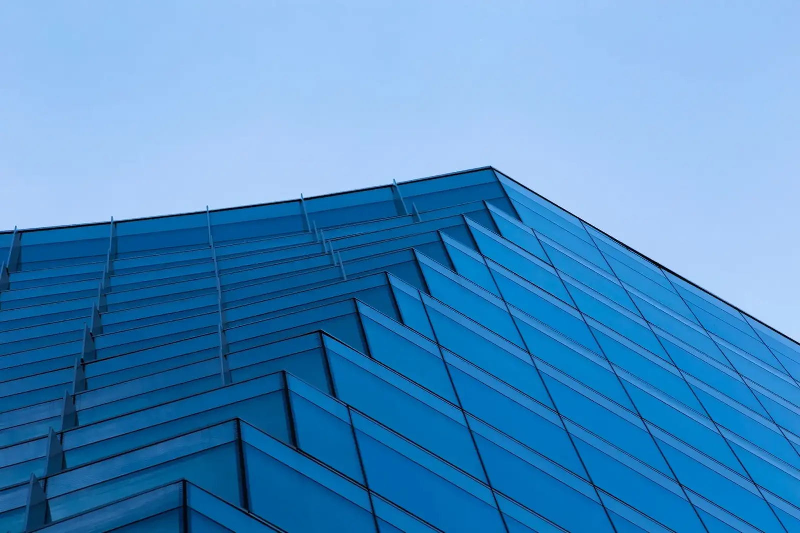 The glass facade of a modern high-rise against a clear sky, the kind of structure an IEC 62305 assessment protects