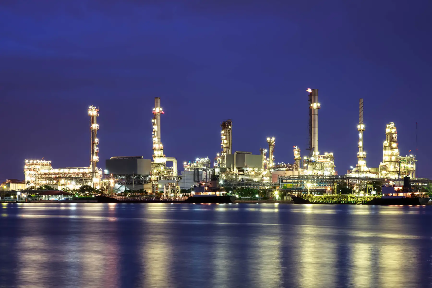 An oil refinery at twilight, where a flammable atmosphere makes a lightning strike a high-consequence event